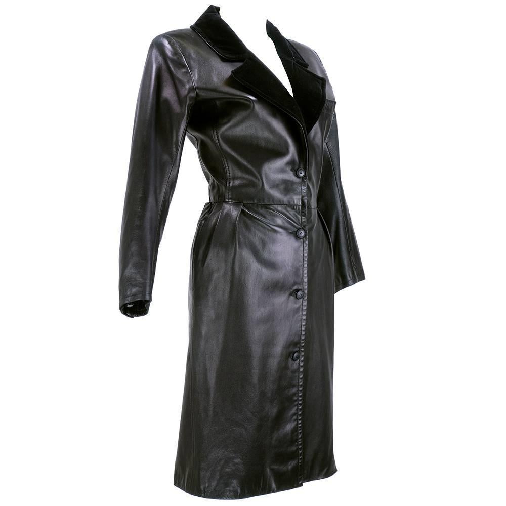 Very dramatic piece by Yves Saint Laurent circa 1980s. Black coat dress style in supple leather trimmed in velvet with a menswear feel. Buttons down front and fully lined. Hidden slash hip pockets.  Slight wear on leather - not noticeable when worn.