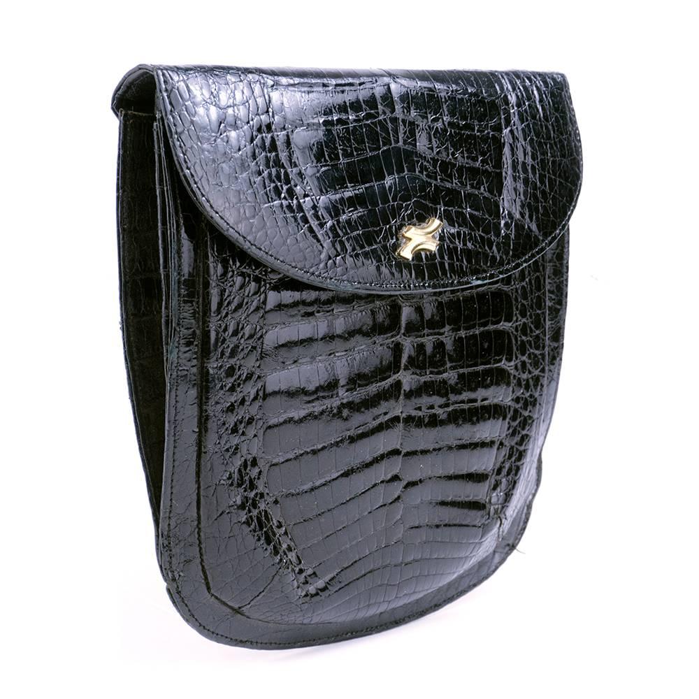 Versatile little cross body pouch of black patent alligator. Gold tone hardware with interior pockets and small hand mirror. Flat body with small accordian pleat.
 
Strap: 41