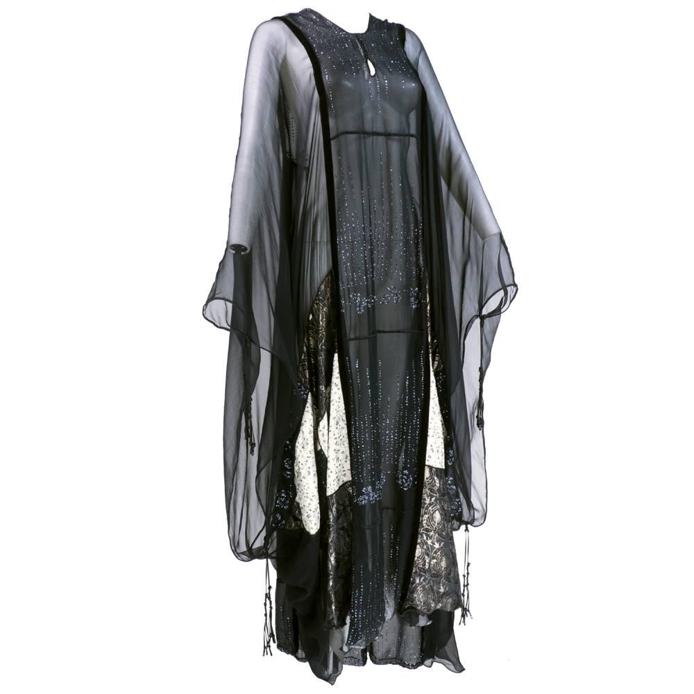 Incredible and iconic caftan by important designer English Thea Porter. Lame jacquard in patchwork panels with black chiffon and velvet trim. Finished with glitter stencils in floral motif.  Signature drop tassles. Even more gorgeous in person. 

