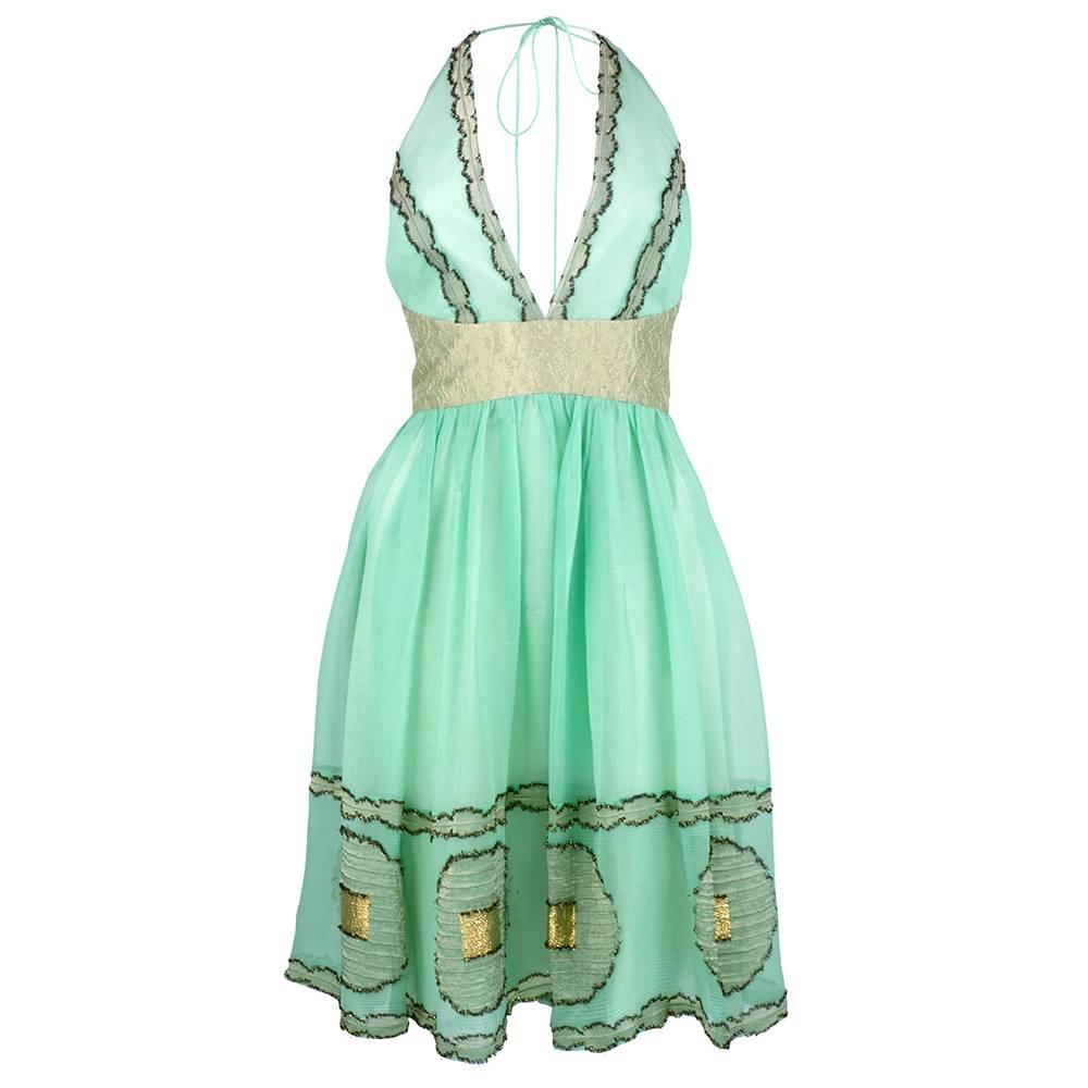 A romantic interlude by the master of whimsy and grace Zac Posen. Fit and flare style party dress in pastel green chiffon with gold lame trim. Tie neck halter top and flared skirt with matching capelet. Fully lined and new with tags. Sexy and sweet.
