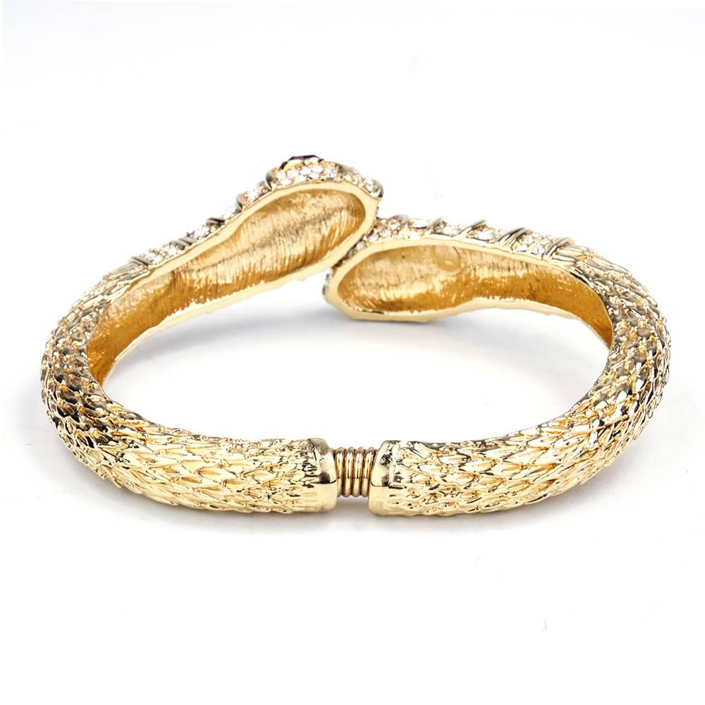 Hardly anything more iconic than this. Kenneth Jay Lane coiled snake head clamper bracelet. In gold tone metal set with clear rhinestones wit faux red ruby eyes. Coiled center widens and closes for secure fit.