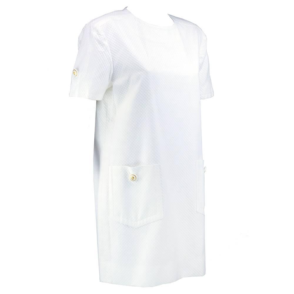 Crisp, white and classic. Chic and short. Boutiques Givenchy white cotton blend pique dress withe padded shoulders  and oversized patch pockets circa 1980s. Fully lined. Perfect for summer.