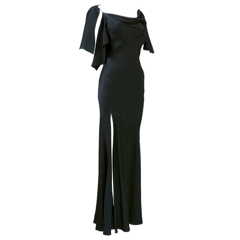 Deceptively simple Black slinky slipper satin gown by John Galliano circa early 2000s. Interesting draped neckline and caped low cut back. High, high slit.  The definition of sexy and sophisticated. Bias cut makes for flexibility in fit  and maximum