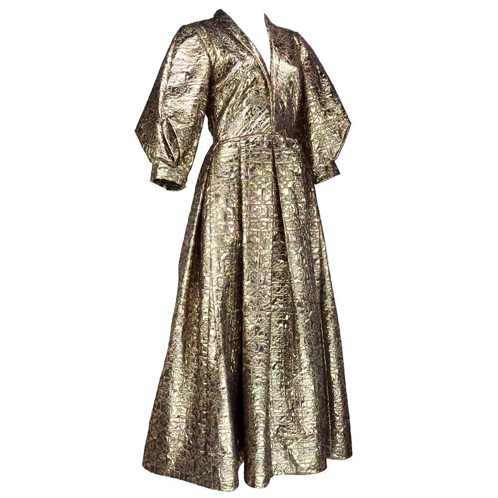 Regal and beautifully structured full length gown by American Master Pauline Trigere. Heavy quilted gold lame with abstract floral motif. Full 3/4 sleeve with low cut shawl collar and full pleatd skirt. Best of all - hidden pockets at hips! 