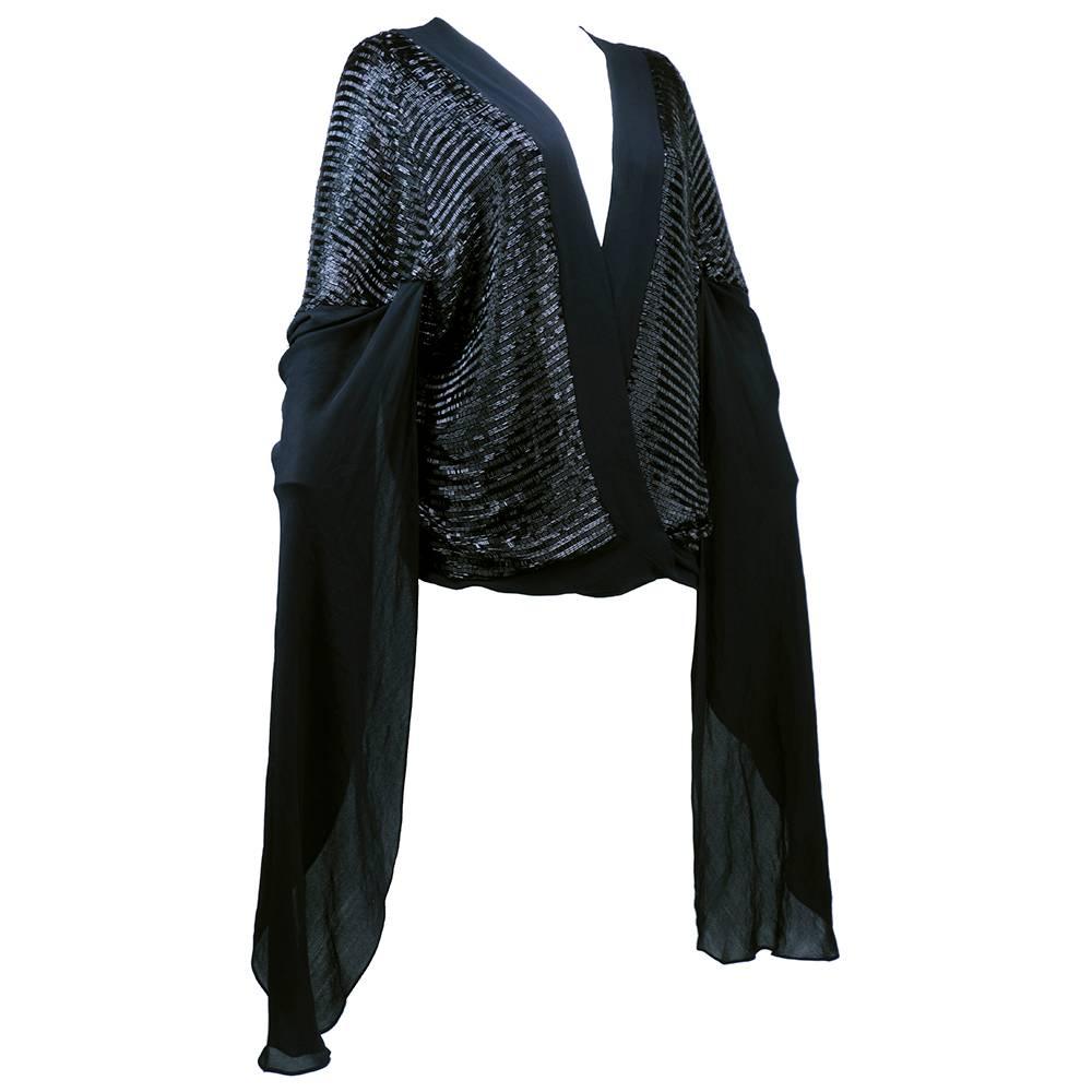 Open front kimono style sheer jacket in black sheer silk circa1930s. Heavily beaded in alternating rows with shiny black bugle beads. Draped, flowing open sleeves. Crosses at waist and secures with a row of snaps. Dramatic and show stopping. Great