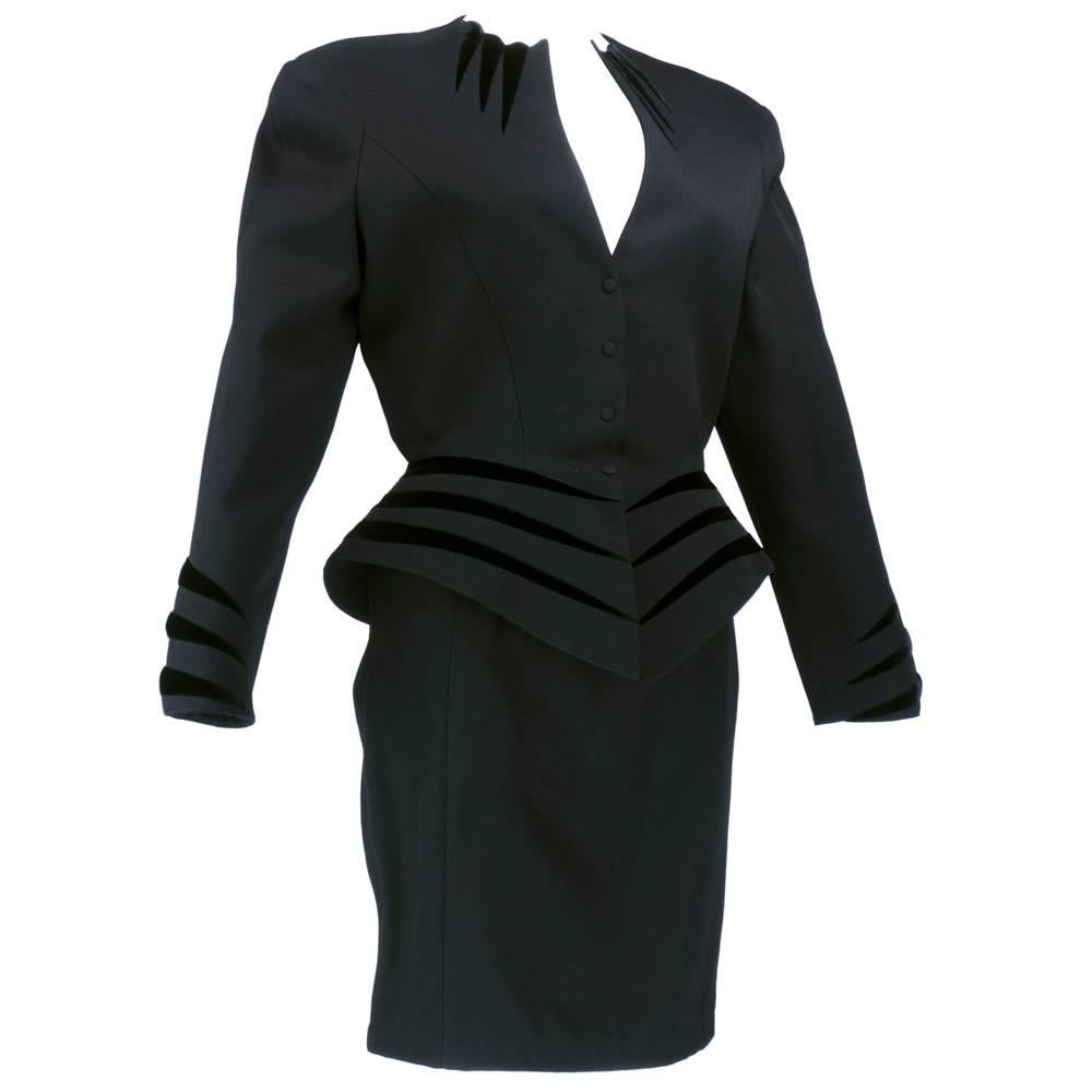 Black gabardine suit by Thierry Mugler circa 1990s. Sci-fi meets the 1940s styling with strong shoulders, extreme  sculpted collar, nipped in waist and sharp peplum. Inset with slashes of black velvet. Snap closures on jacket.  Slim lined pencil