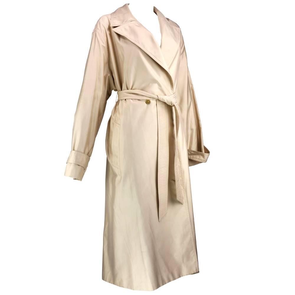 Feraud circa 1990s. Lightweight rayon/poly overcoat in tan with double breasted detail with wide peaked collar. Detached sash belt. Deep slash pocket. Can be worn for casual or dressy use.  Timeless style.