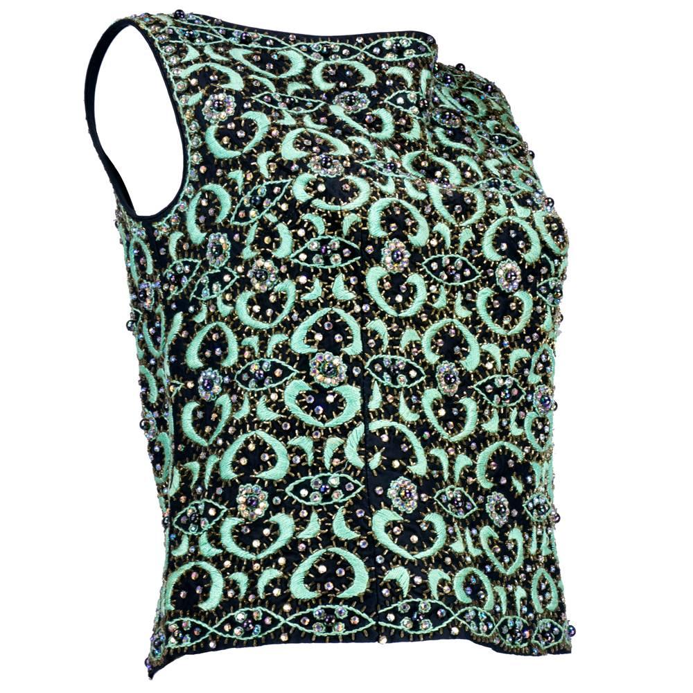 Beautifully executed allover surface design on this sexy, sleeveless shell from the 60s.  Mint green hand embroidery enhanced with topaz bugle beads and aurora borealis prong-set crystals.  All sewn on a black rayon and fully lined.  Zip back. 