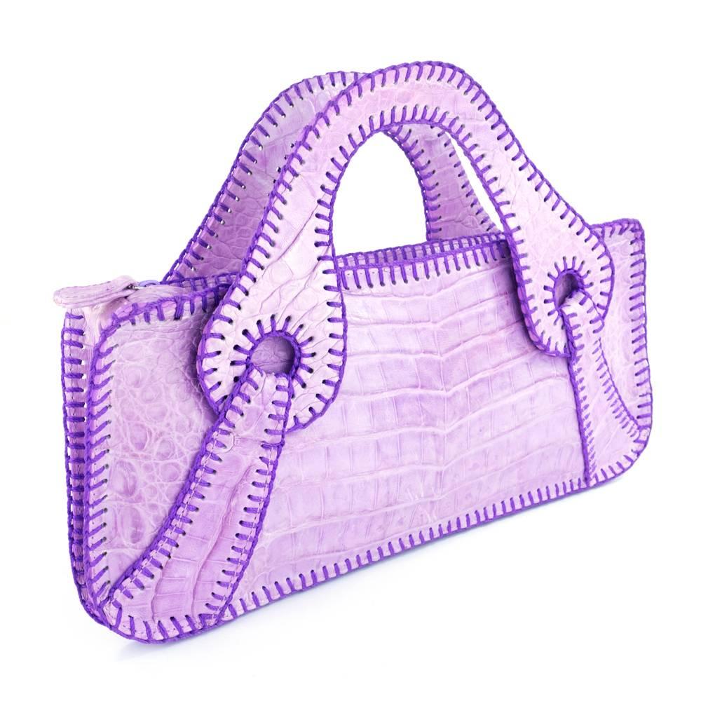 Modern styling with classic touches. Supple and soft dyed alligator purse by legendary handbag designer Carlos Falchi. Zip top and lined in suede. With complementary purple top stitching. Double handles - Lays flat but has fold to expand. Quite a