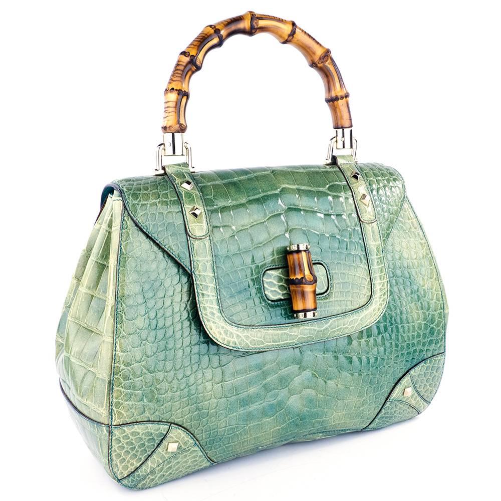 A gorgeous handbag from Gucci done in luxurious, brilliant mint green alligator. Complete with classic bamboo hardware, this signature Gucci bag is a work of art.

Measurements--
Length: 12 1/4 inches
Height: 10 inches
Depth: 4 inches at base; 2