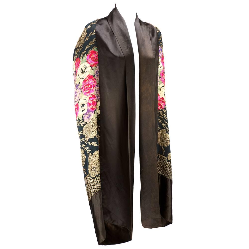 Flapper era deco opera cape in floral gold lame edged in black satin. S dramatic and romantic. Draped in back. Slight discoloration on black satin throughout adds a nice patina to piece. 