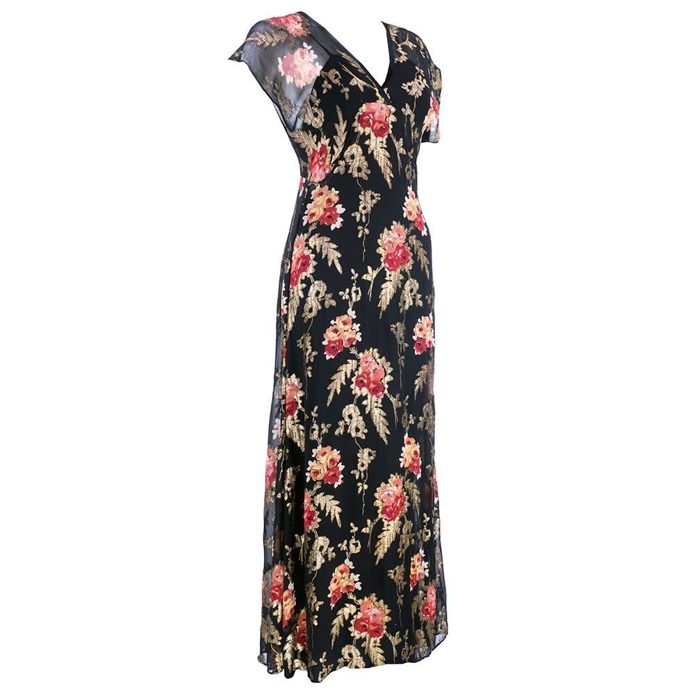 1930s deco style evening gown in black silk chiffon and lame bias cut with vibrant painterly floral pattern.  Dramatic 9 1/2 inch train. Sheer and lightweight with low cut back.