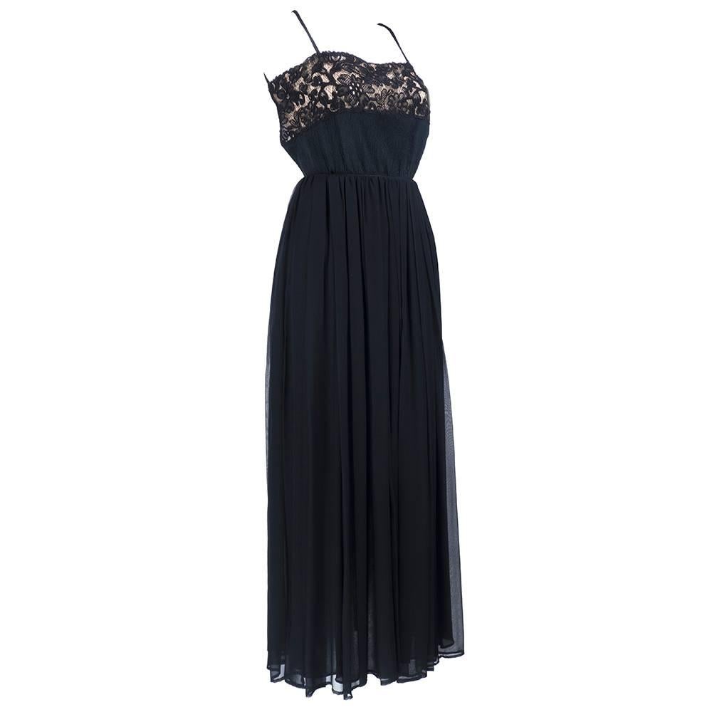 An ultra sexy evening gown from Galanos done in silk, chiffon and lace circa 1970s. Featuring a black lace on nude bodice, the skirt is made of luxe flowing chiffon. The back is cut low and ties. Zipper back closure. 