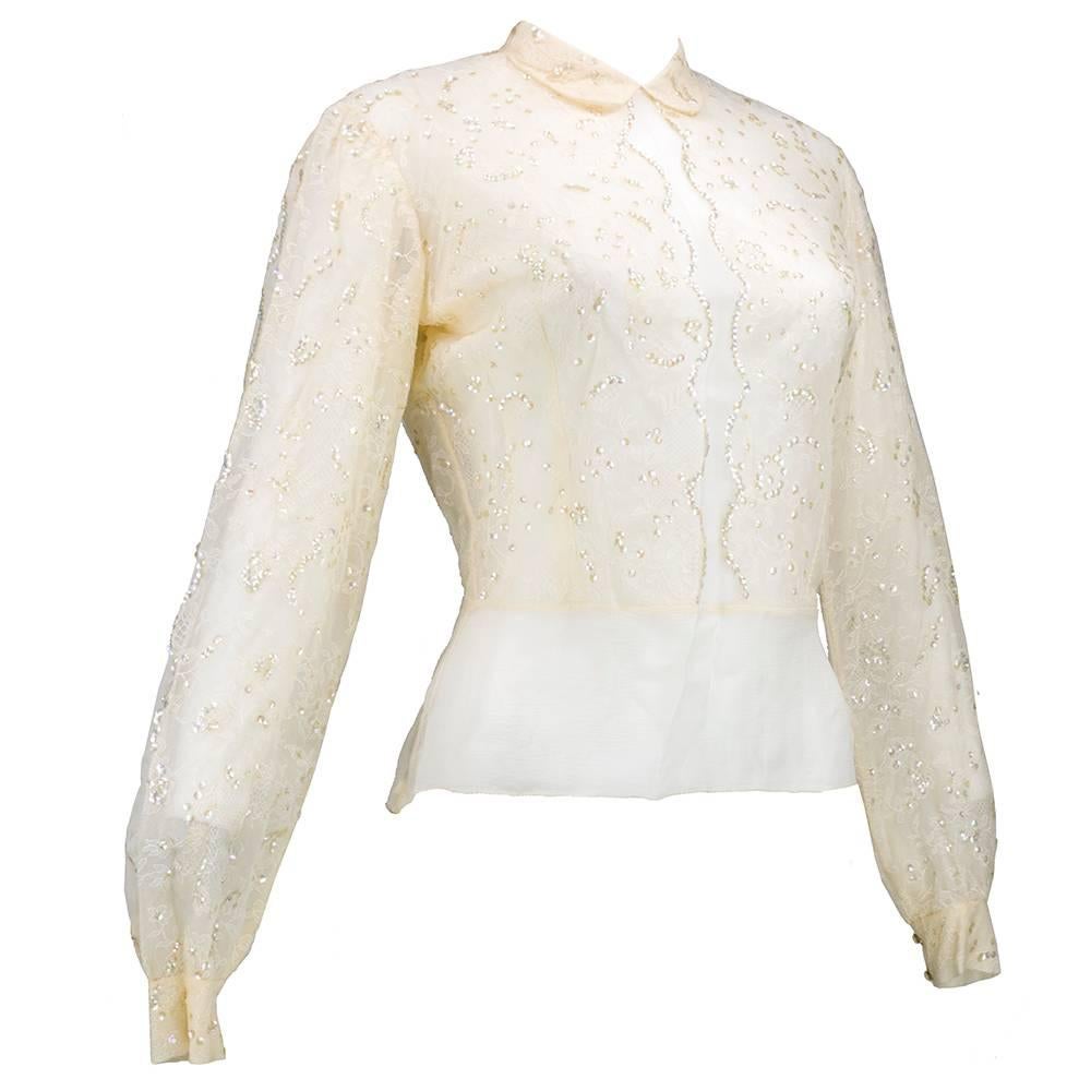 Delicate and lovely couture evening blouse by from the french house of Andree Viallard.  Ivory chiffon overlaid with chantilly lace and accented with iridescent sequins. Sheer with peter pan collar . Tiny covered buttons up back and on cuffs. The
