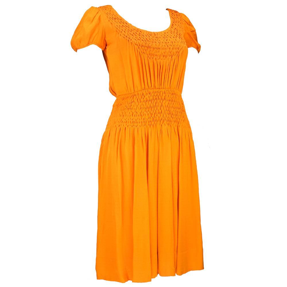 Incredible 1970s dress by Christian Dior-New York.  Orange silk peasant style with hand smocking detail at bodice and waist, reminiscent of Eastern European dresses from the 1920s.  Fully lined with poufed cap sleeves. 