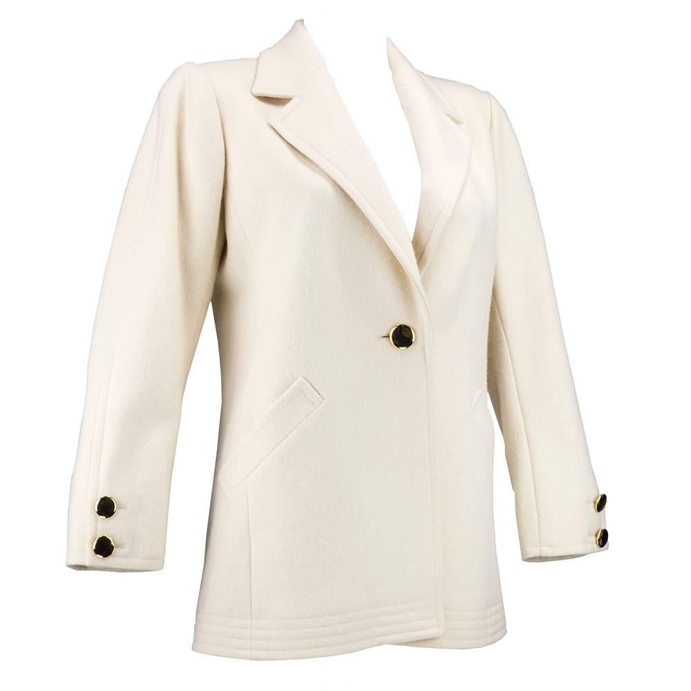 Practical and chic by the iconic Yves Saint Laurent. Ivory wool blazer cut car coat style with strong padded shoulders. Fully lined with slash pockets and bright brass buttons. Timeless, effortless chic.