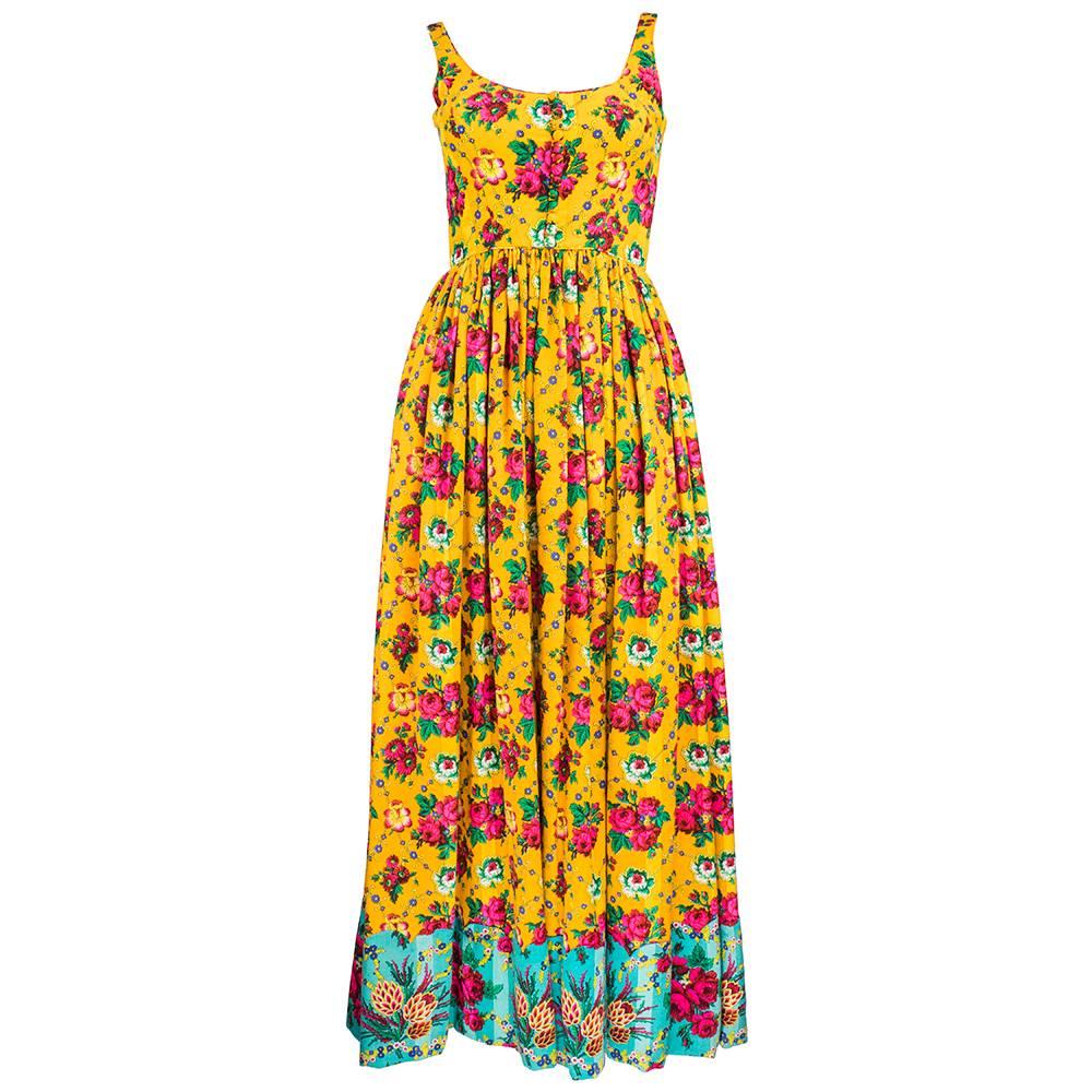 Whimsical and colorful 1970s era maxi dress with matching cropped jacket.  Wool blend with floral print in tones of gold, magenta and with a contrasting turquoise floral print appliquéd to hem and jacket.  Self piping edge around neckline and waist.