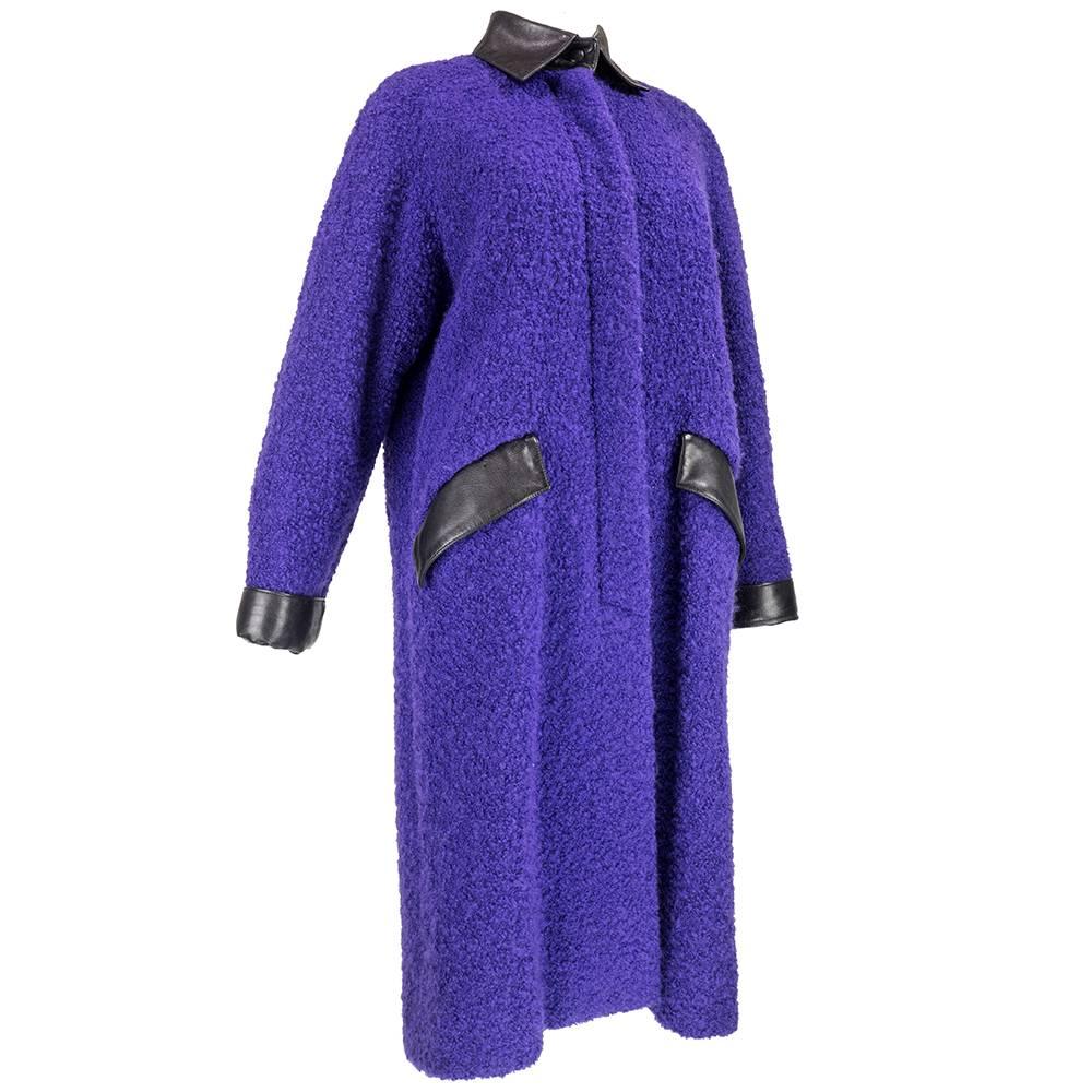 Dramatic and vibrant purple overcoat in nubby wool by Christian Dior. Collar, cuff and pocket trimmed in supple black leather. Lined in silk. Hidden buttons down front. Some discoloration throughout lining - cannot be seen when worn and does not