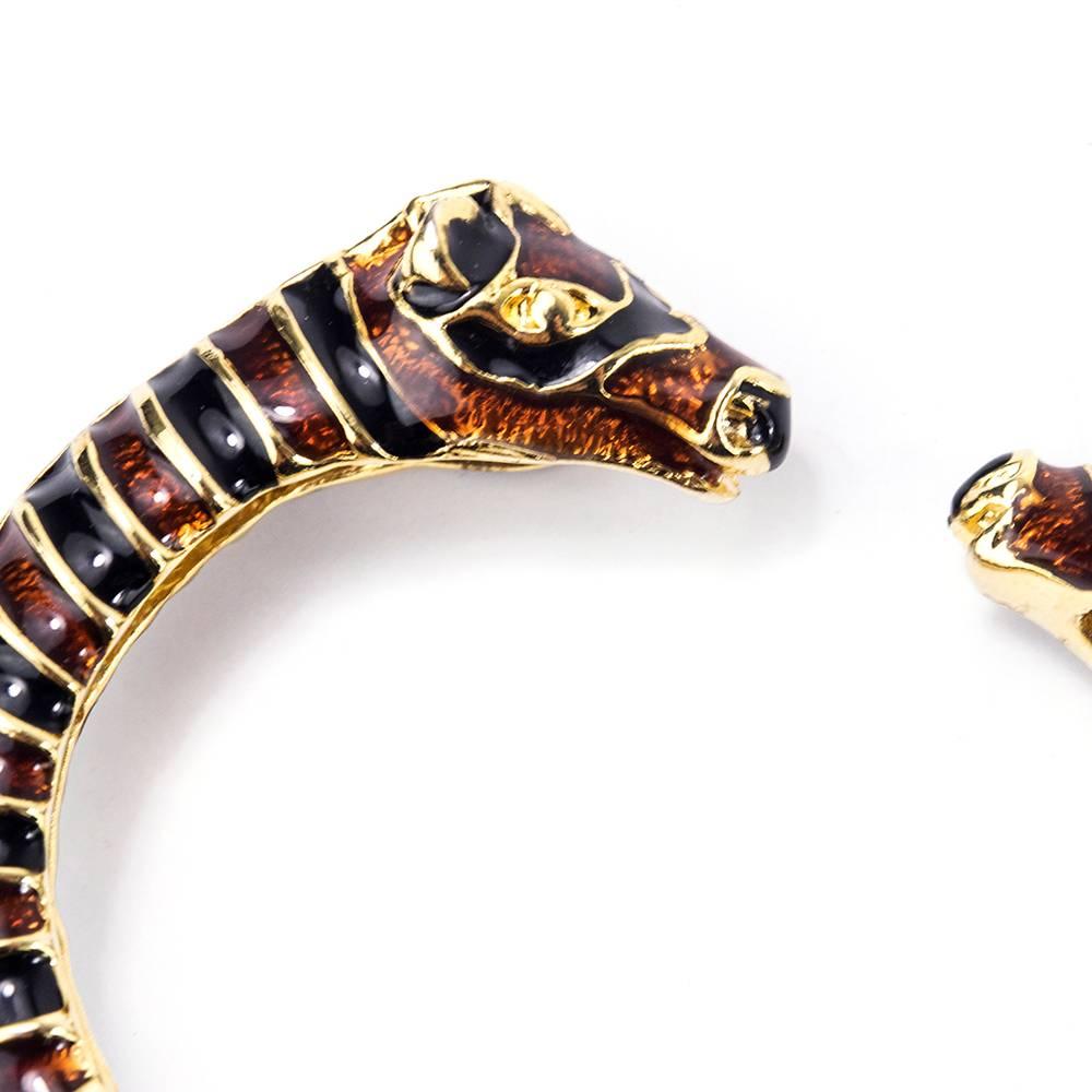 Diminutive and chic classic by Kenneth Jay Lane circa 1980s. Stylized giraffe heads on spring loaded open bracelet. Nicely weighted and well balanced. Timeless, forever piece. Sizing slightly flexible to open style and spring hinge.