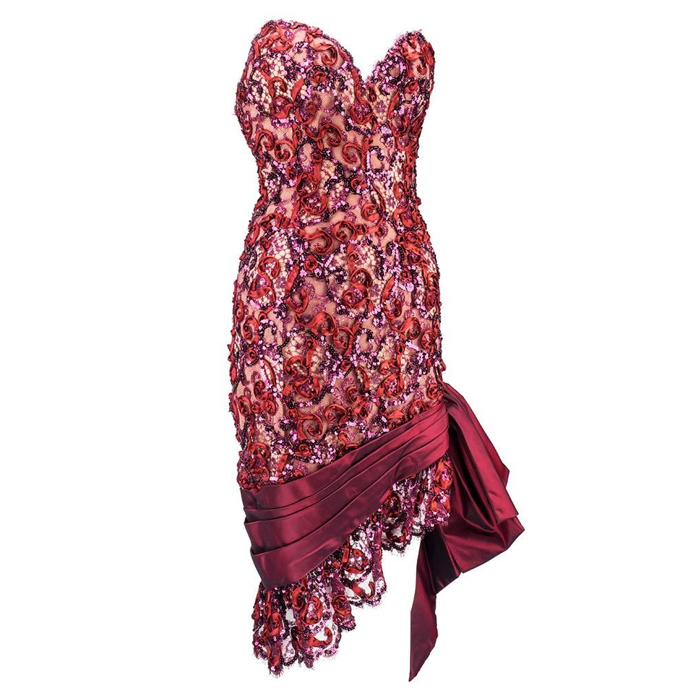 This fabulous 1980's cocktail dress, attributed to iconic American designer Bob Mackie, is covered in bordeaux red metallic lace embellished with silk ribbon and iridescent sequins. Sculpted, strapless bodice has a sexy plunging neck and