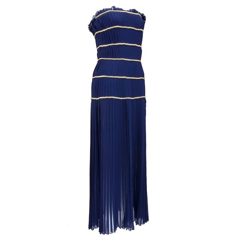 Absolutely stunning Chanel gown, done in intricately pleated navy silk chiffon and accented with iconic Chanel gold chain. Zips and buttons at side. Structured, boned  bodice. Skirt sheer and pleated to ground. A grand entrance maker.