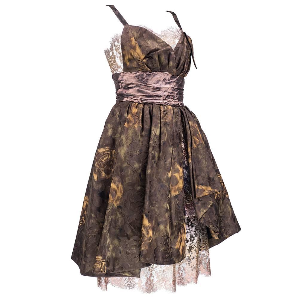 Sexy and luxe party dress from Christian Lacroix is done in a chocolate brown floral silk jacquard woven with deco roses. Asymmetrical bodice is lined with metallic gold lamé lace and cinched with loosely pleated waistband. Full and flirty skirt