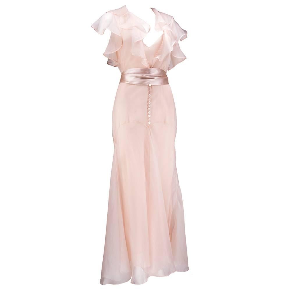 A true stunner - a crisp powder peach silk gown by Ralph Lauren's purple label circa early 2000s. Loosely ruffled shawl collar with matching fanned sleeves. Delicate dyed mother of pearl buttons down front leaving open slit down skirt. With matching