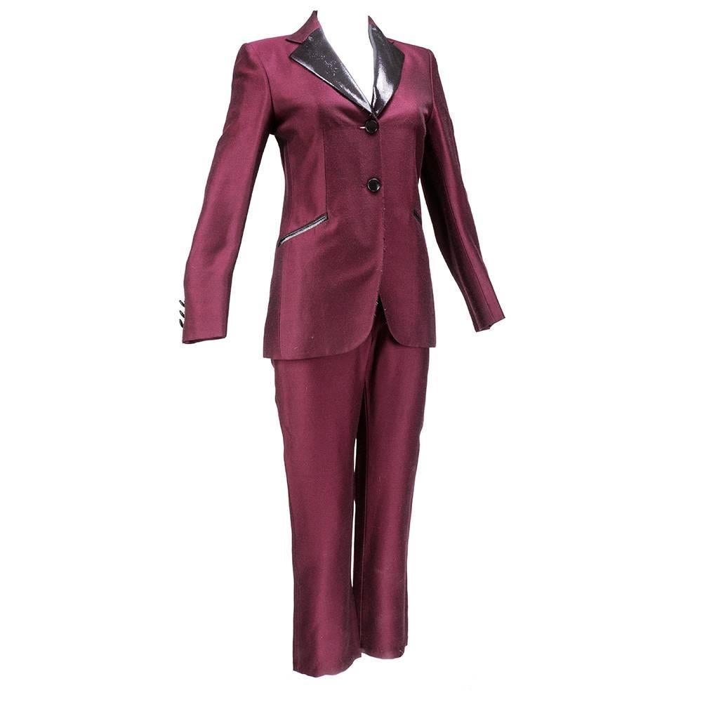 Chic, cropped tuxedo suit by Moschino circa 1990s. Wool acetate blend in slightly iridescent deep burgundy with black lurex trim.  Two button styling and fully lined. Close fitting jacket and cropped, high waisted pants. Faux slash pockets on