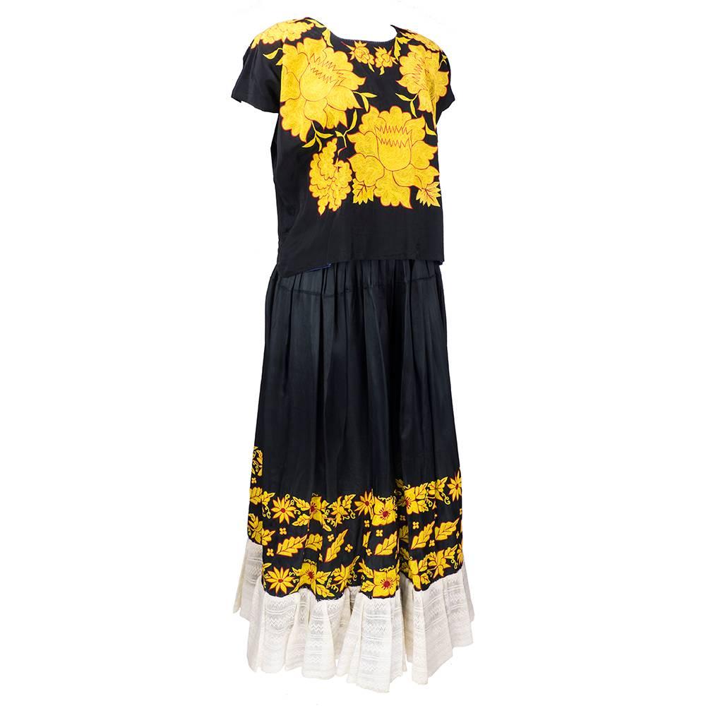 Wonderful example of Mexican folkloric ensemble. Consisting of traditional style blouse of black with gold floral embroidery throughout with full sweeping lace edged hem.

Skirt-
Waist: 30 inches
Length: 37 inches