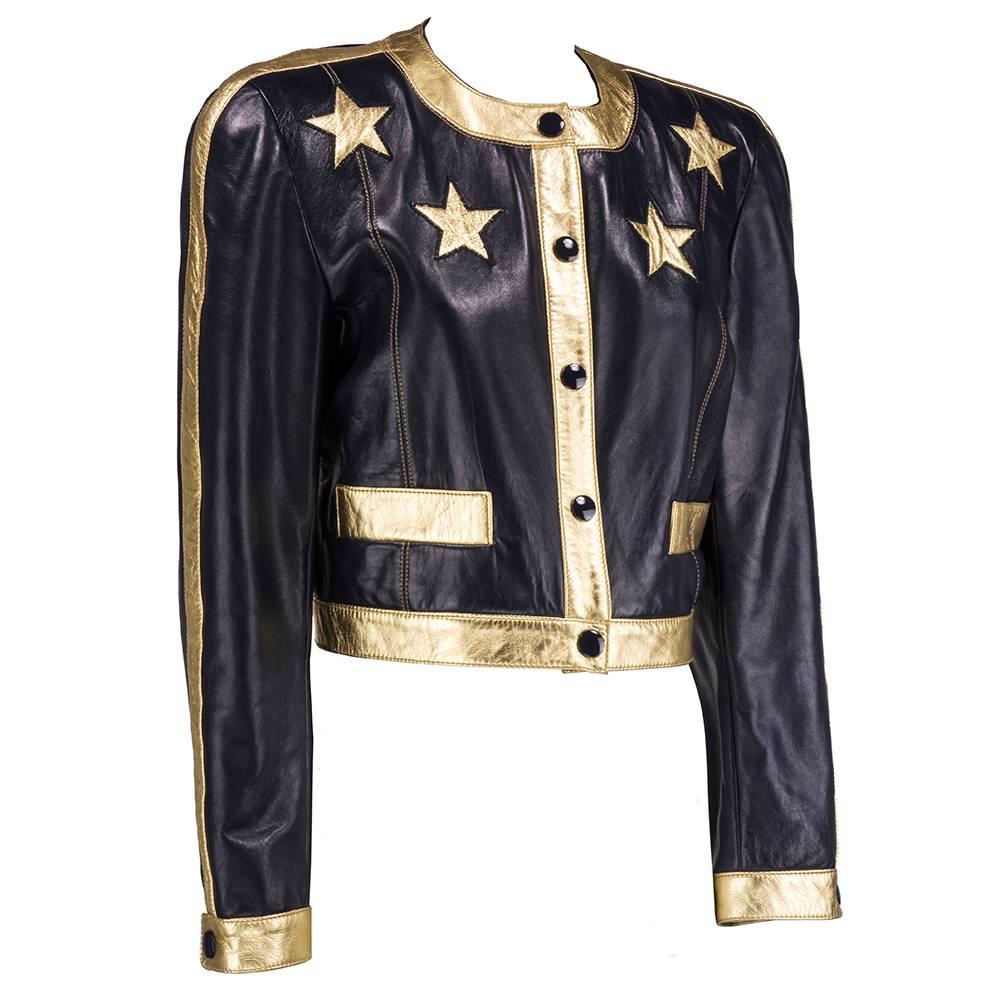 Literally star studded cropped leather jacket by Escada circa 1990s. Black with gold trim and stars. Snap closures. Double front pockets. Padded shoulders and contrasting stitch. Fully lined.
