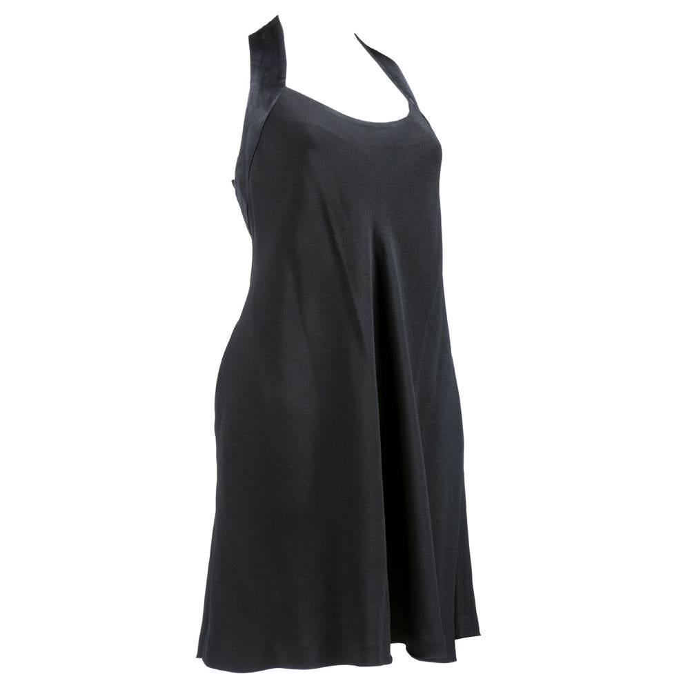 A black crepe dress from Moschino Cheap and Chic, cleverly accented with black satin straps that form a peace sign in the back. Dress features a flowing skirt and slash pockets.  A true statement dress!
