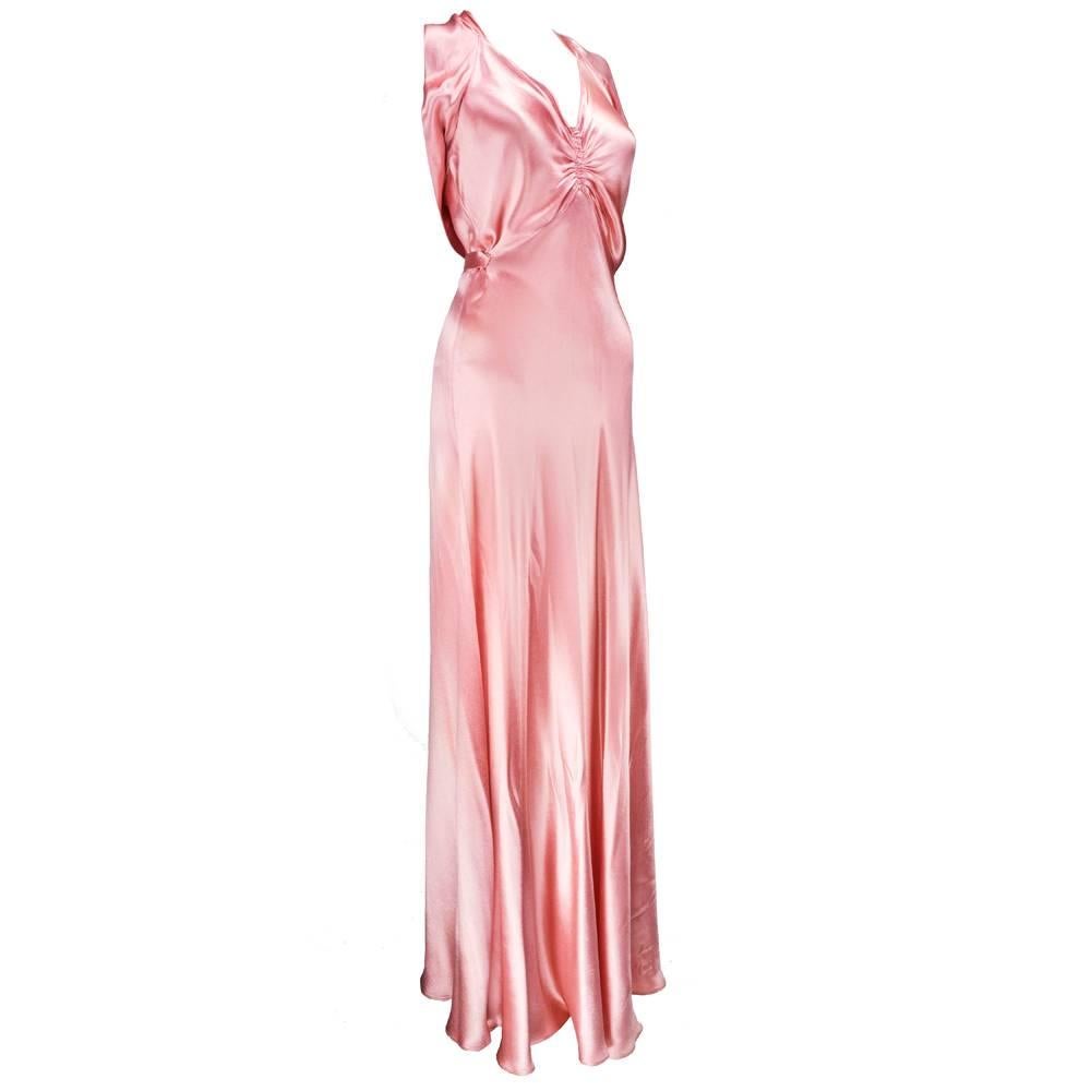 Stunning slipper satin gown from the 1930s in blush pink. Cut on the bias. Shirred at bust, draped at bodice with halter neck.  Covered buttons down back with self belt.  A gown Jean Harlow would have loved. Sizing flexible due to bias cut.  An