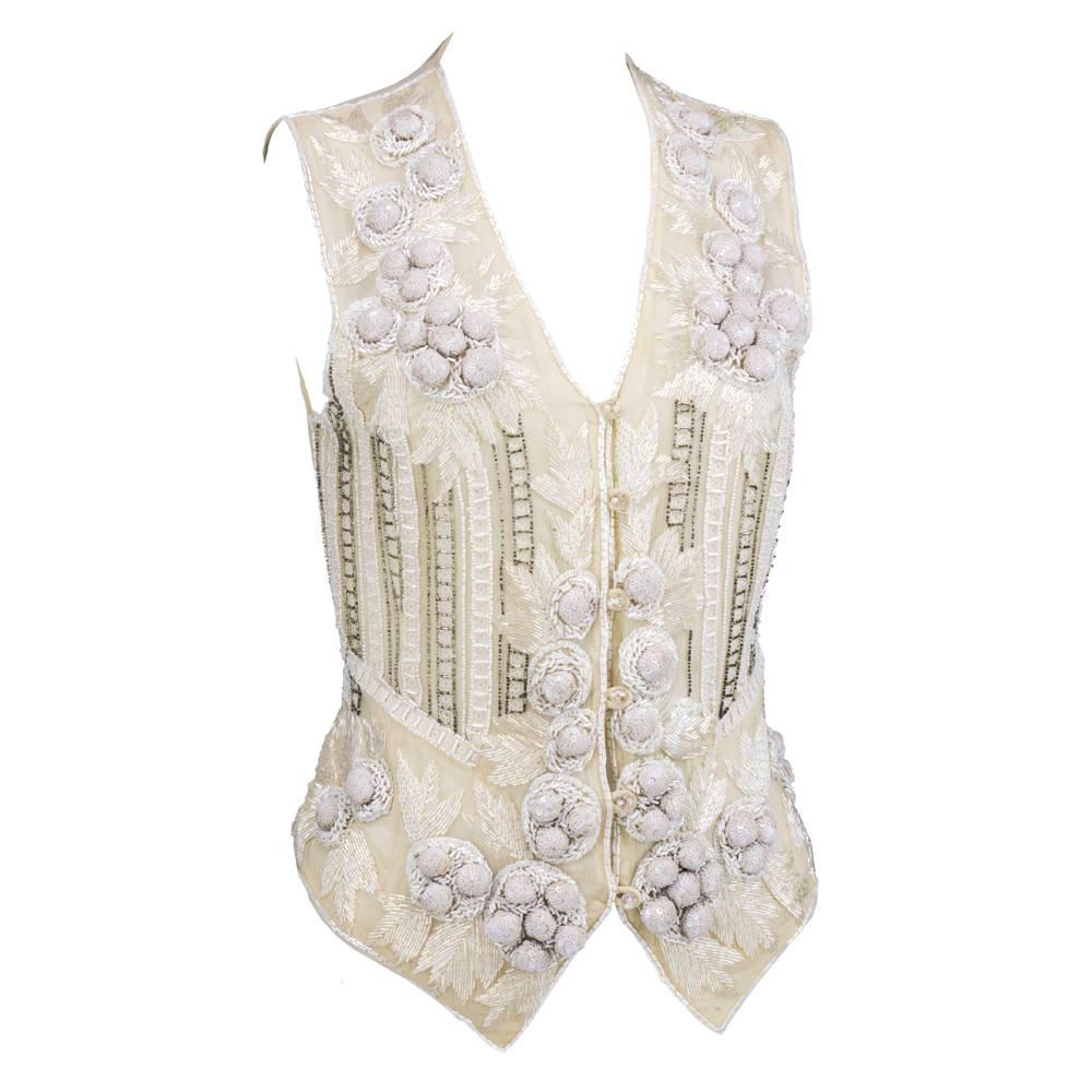 Circa 1990s beautifully beaded and sequined white chiffon vest by British label Eavis and Brown. Renowned for their luxurious embellishments - this piece does not disappoint. Sheer, fully lined with iridescent gem buttons with hook and eyes.