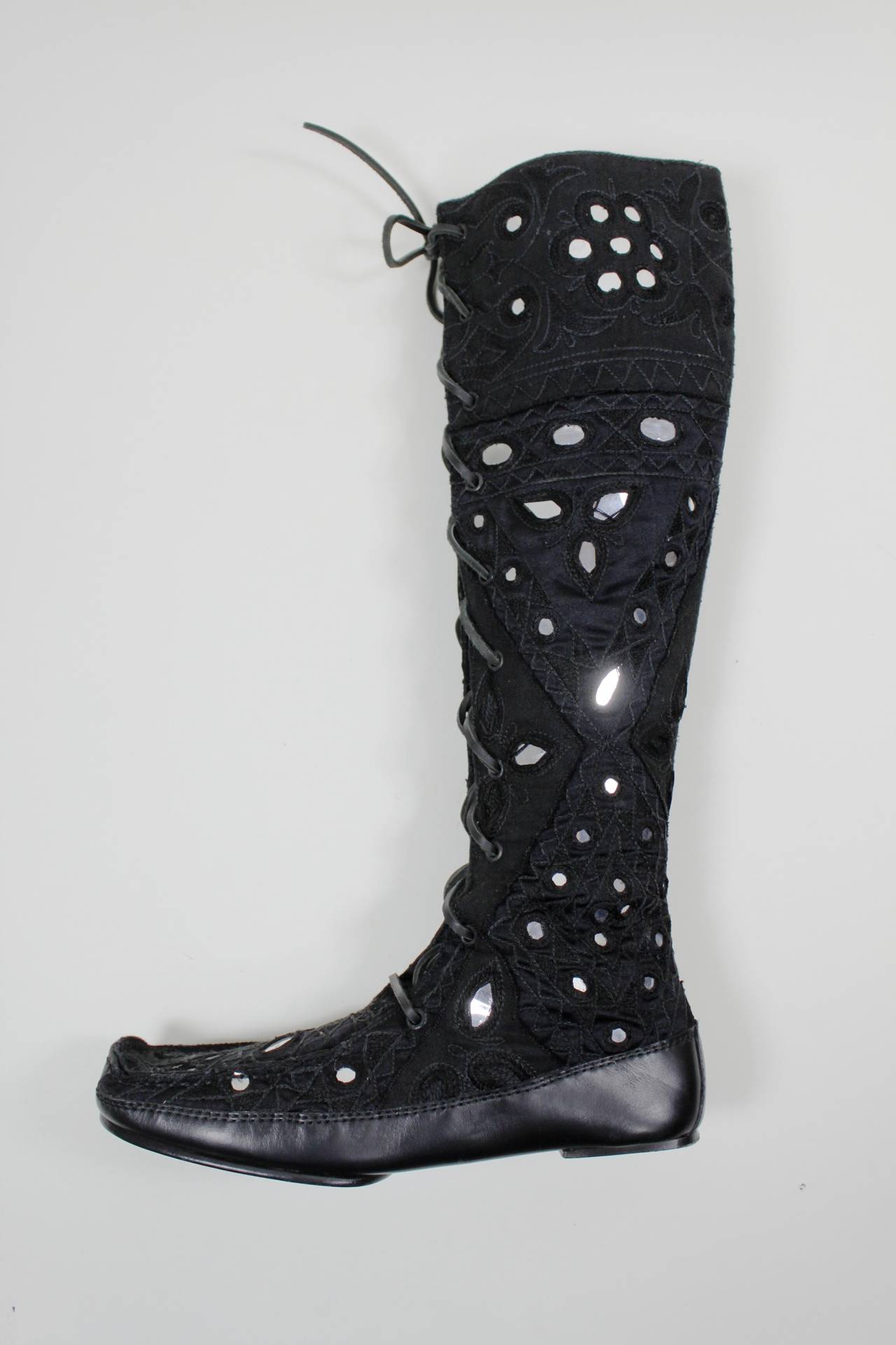 These boots are the perfect way to ease into Spring! The black embroidered knee-high boots featured textured embroidery and mirror appliques throughout. They lace up with thick leather cord.

-Size 7
-Leather sole
