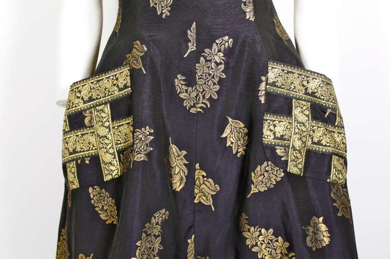 Black and gold brocade. Apron style. Oversized pockets at front. Criss-cross back. Back zipper closure.