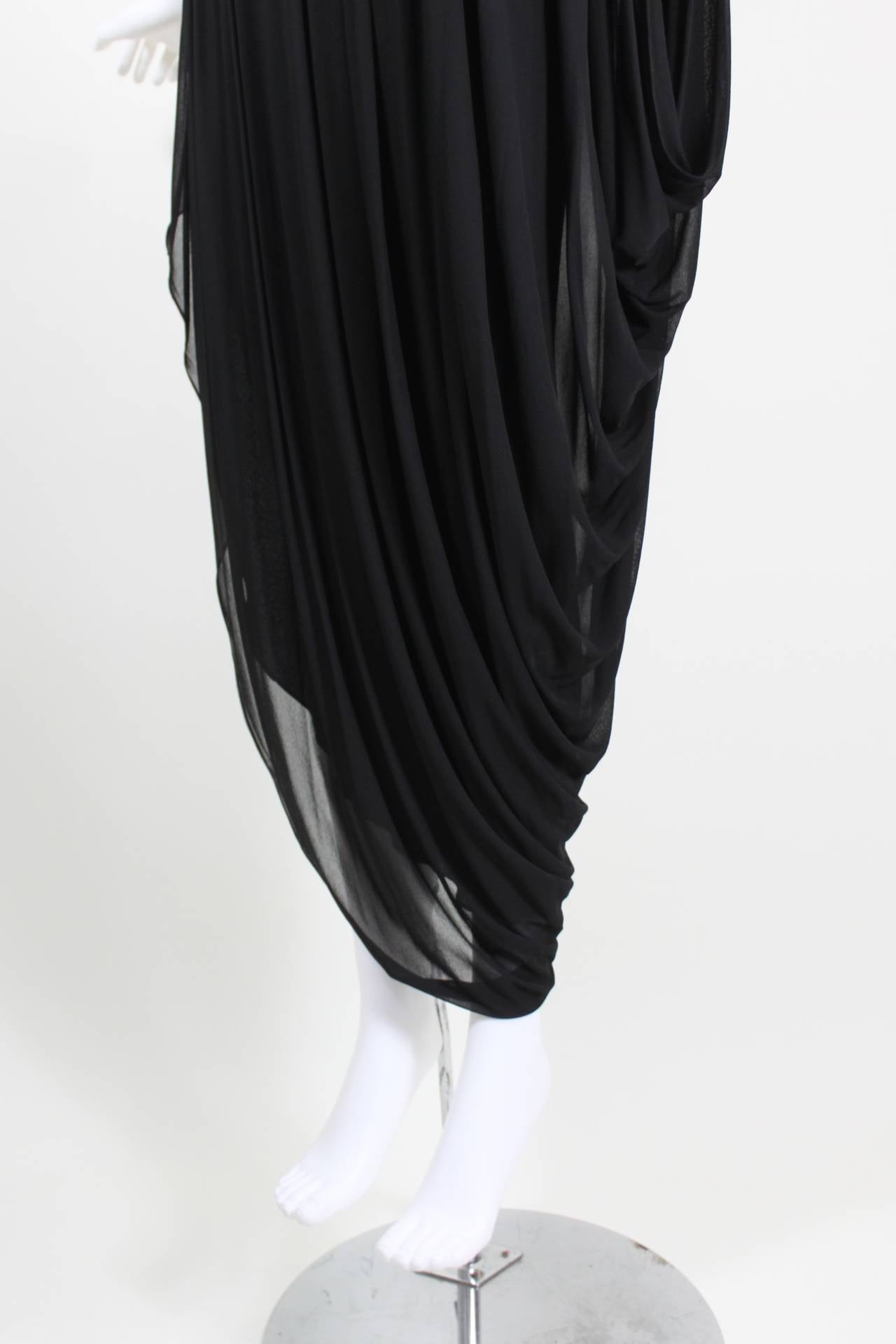 A fabulous evening dress from Bob Mackie. Luxe black jersey is draped along an asymmetrical seam, allowing for a cocoon hem. A white and silver beaded tulip accents the bodice.

-Zips in back
-Fully lined

Measurements--
Bust: 36