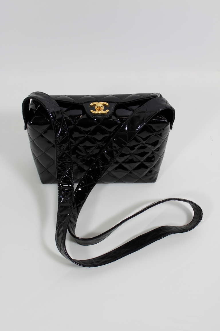 A wonderful black patent leather purse from CHANEL. Quilted throughout and topped with a gold-tone quilted double-C closure. Pocket in back of bag, and zipped pocket inside. Folded closure on top of purse. Please not the shoulder strap is not