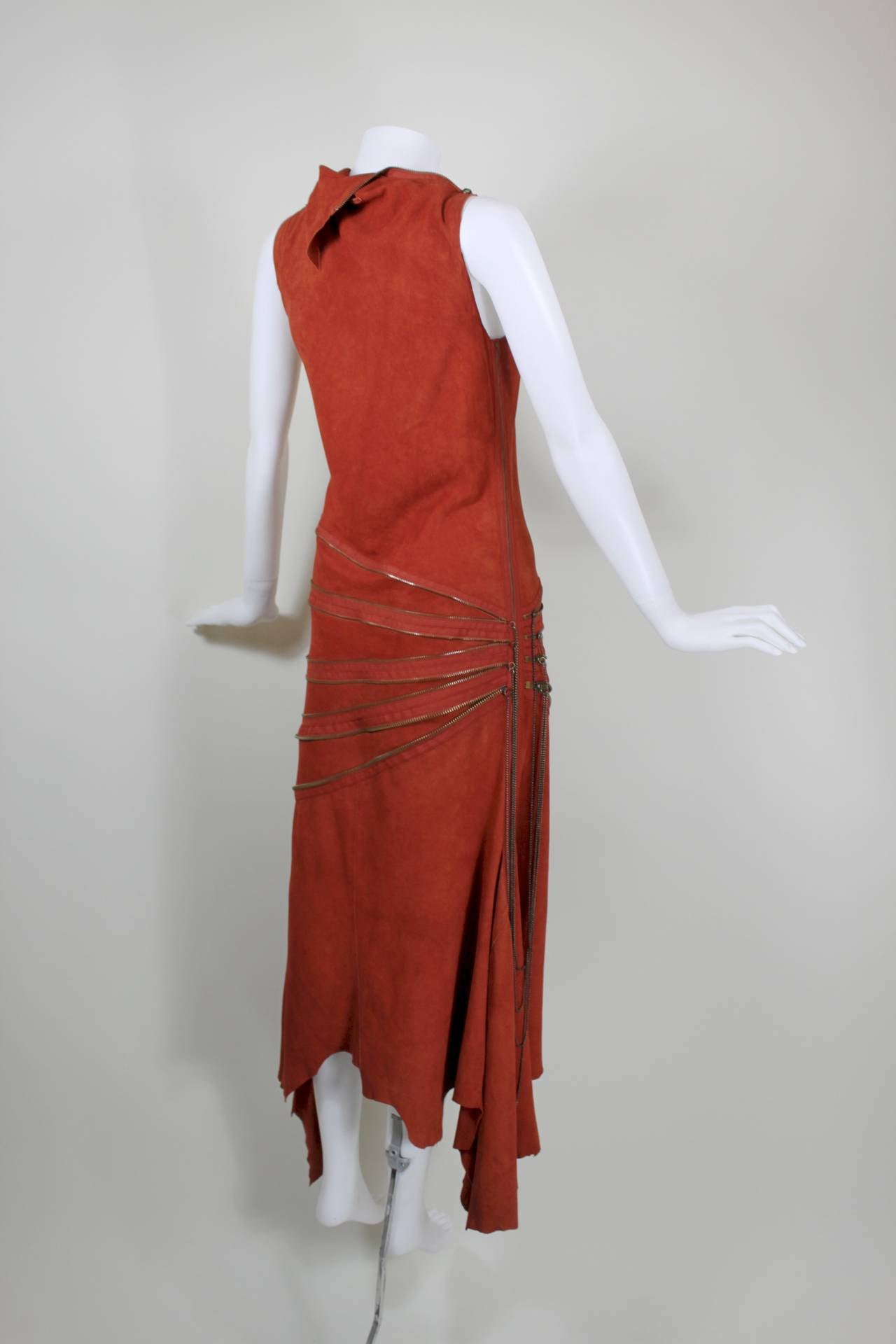A luxe burnt rust suede dress from Jean Paul Gaultier, featuring four rows of fully functioning zippers to adjust the asymmetrical silhouette. A jagged hem adds movement in the skirt.

Meausrements--
Bust: up to 36 inches
Waist: up to 30