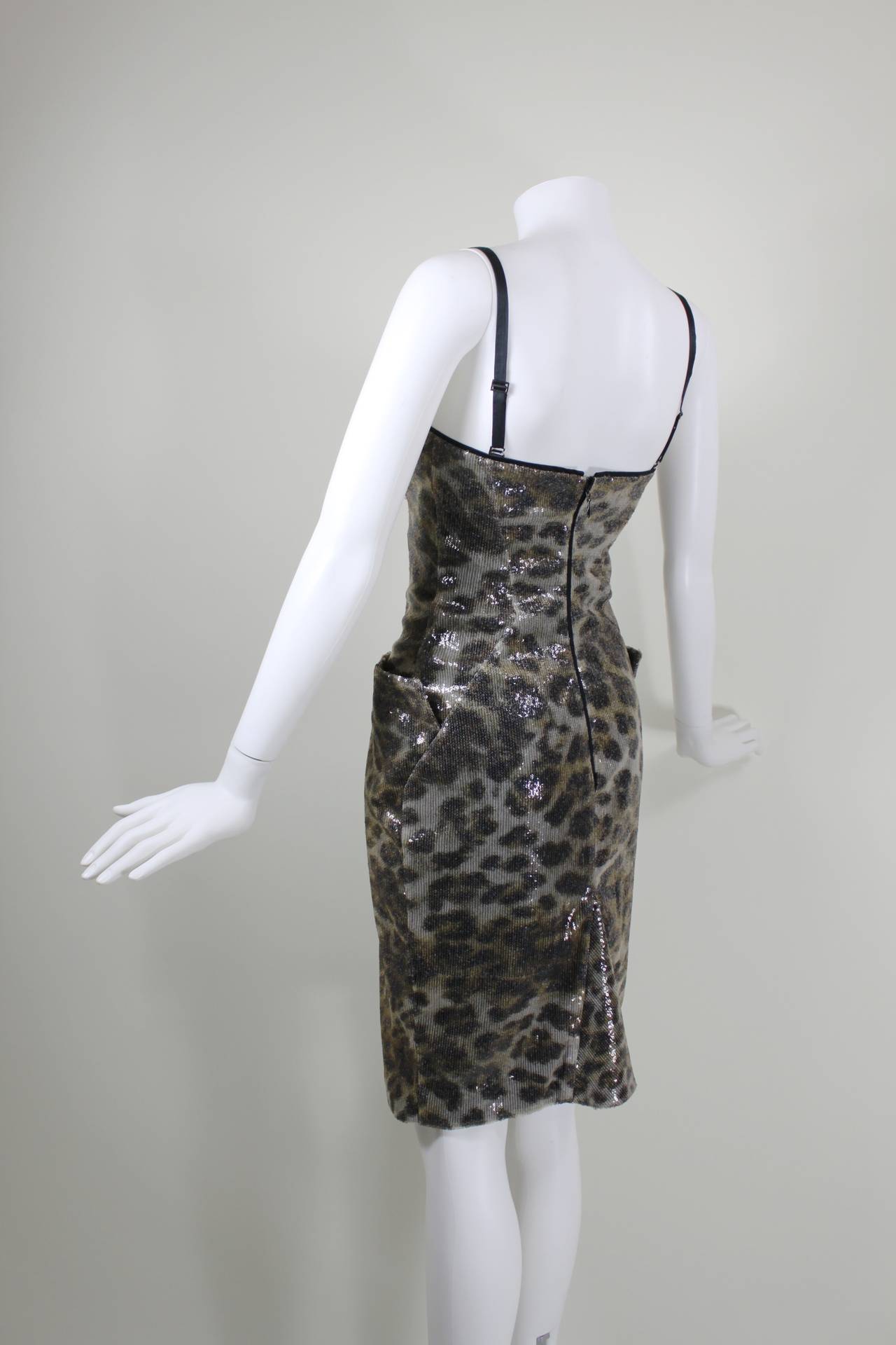 An architectural, sexy cocktail dress from Vivienne Westwood. The bodice is crafted into the designer's signature bustier silhouette and features two structured pockets at the hip. A playful leopard print is accented with a clear sequin overlay to