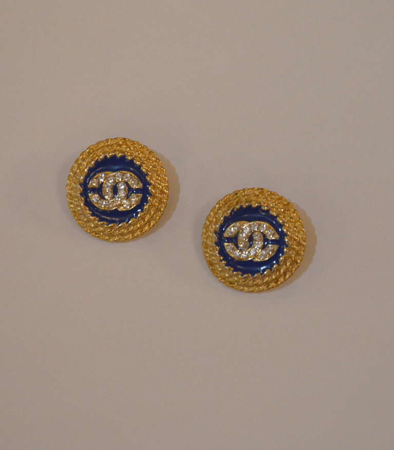 Classic CHANEL logo button earrings. Gold plated with blue enamel and featuring rhinestones. Clip back.