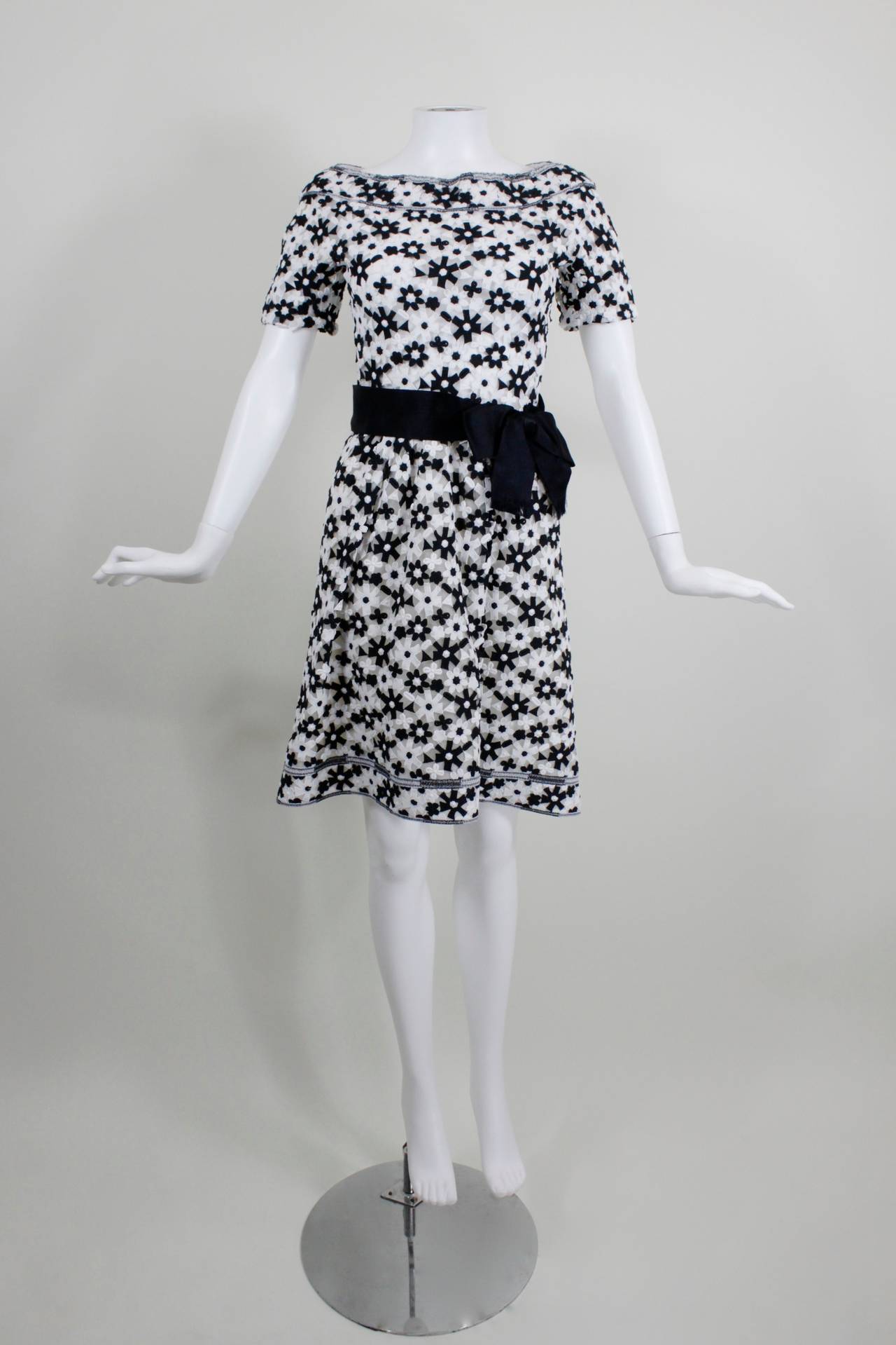 A fun and flirty cocktail dress from Arnold Scaasi. Black and white daisies are embroidered on tulle net throughout the dress. Waist is cinched with a black satin bow belt (sewn on and closed with snaps).

Measurements--
Bust: 34 inches
Waist: