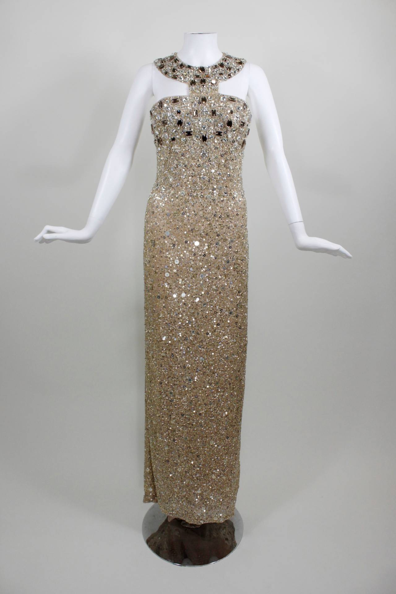A stunning gown from the great American designer Oscar de la Renta. The Egyptian collar-inspired bodice features large brown, clear, and champagne glass rhinestones, as well as metallic sequins and beads throughout. The gown is fully lined, has a