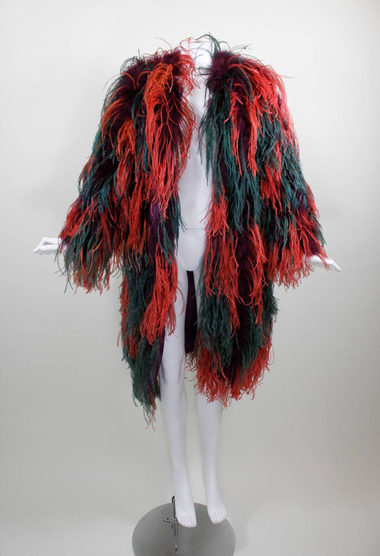 A wonderfully wild coat from Yves Saint Laurent featuring teal and bright brick red ostrich feathers as well as purple marabou throughout. The coat buttons at the neck with a hook and eye, and is fully lined.

Measurements--
44 inches across