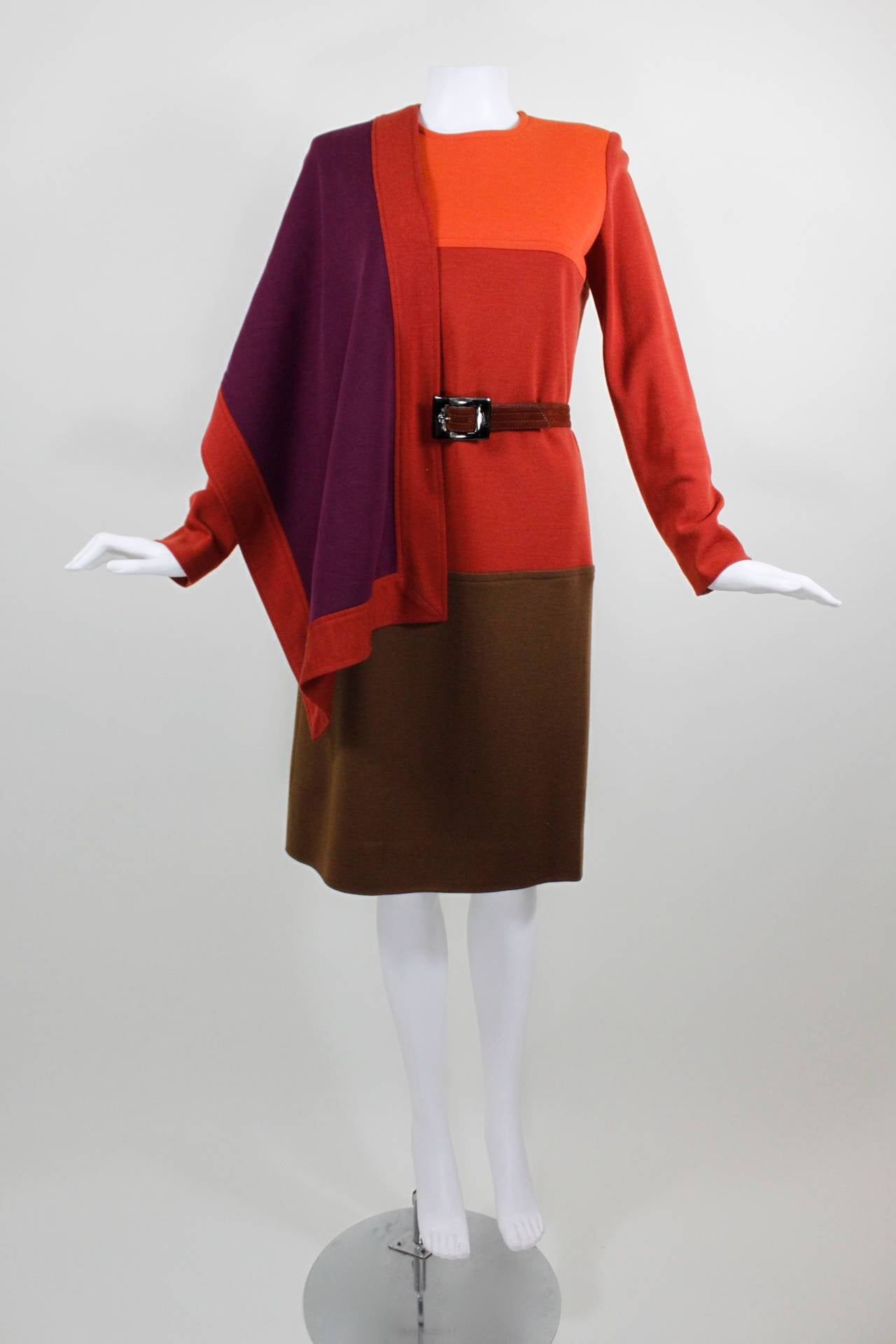 This is the perfect fall dress from YSL. Shades of orange, magenta, and hazel come together beautifully in this colorblocked wool dress. A high neck and long sleeves are balanced by a cocktail-length hem. The dress has an accompanying stole and