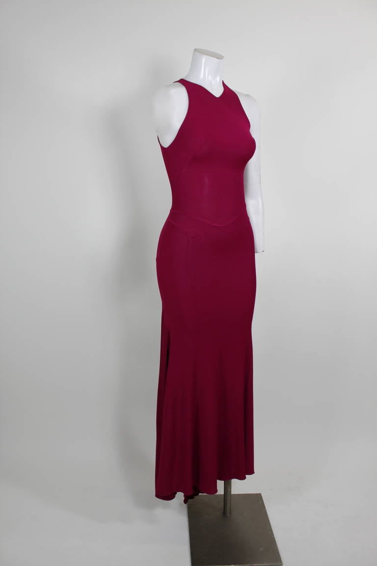 An ultra sexy gown from Alaïa done in the label’s iconic jersey knit. Body skimming and chic, the gown features a racer neckline and slight train in the back. Side zip. Unlined. Bias cut. Hook and eye at neck. 
