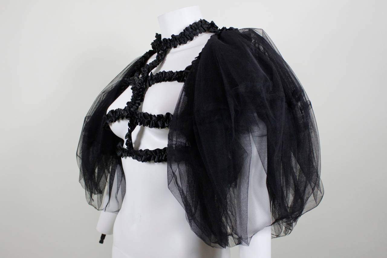 An interesting, versatile blouse from Comme des Garçons. Full black tulle sleeves add volume to the simple ruched black satin ribbon cage bodice. Can be worn alone or over a gown, tshirt, anything!

Marked a size Large, but is generally free in