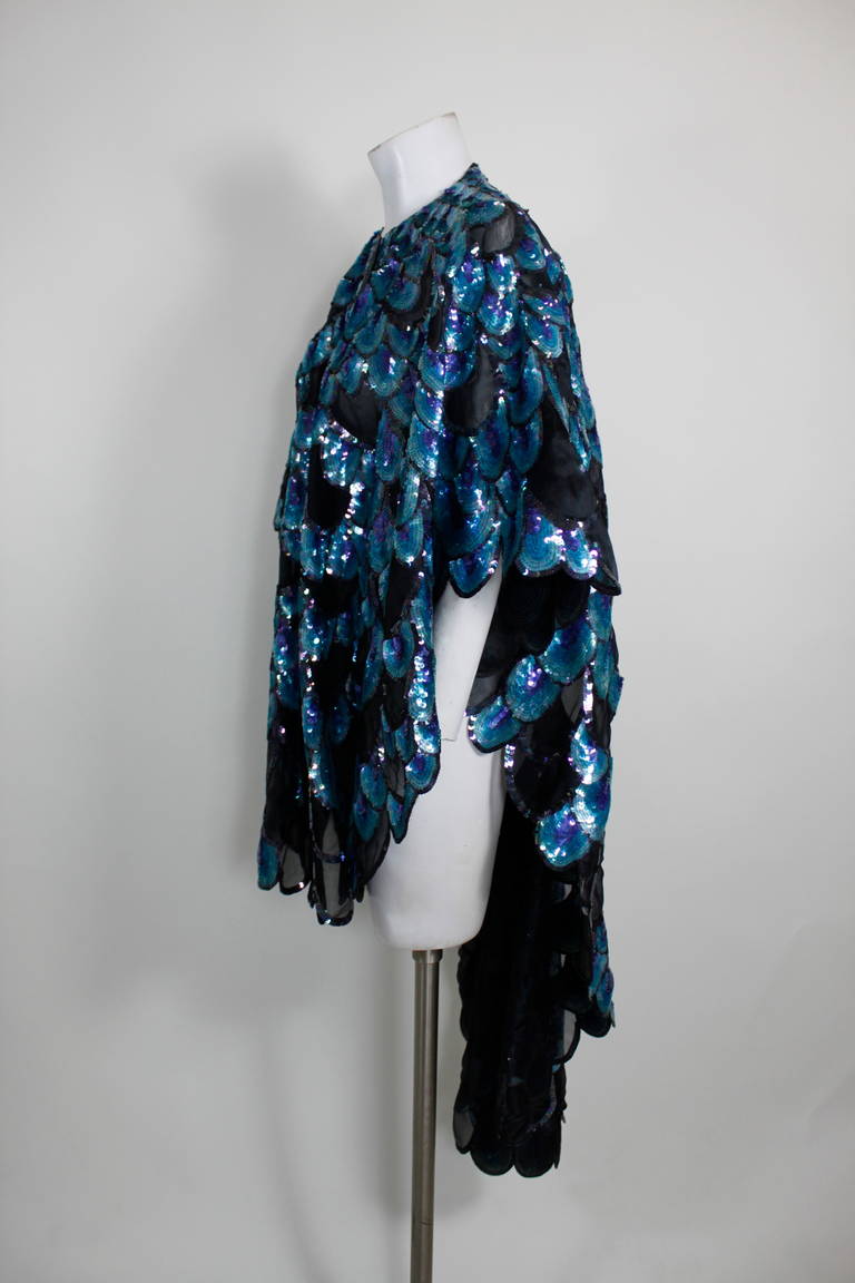 A fab peacock motif multicolored sequined cape. 

Measurements--
Length: 50 inches
Length, Shoulder to Shoulder: 41 inches