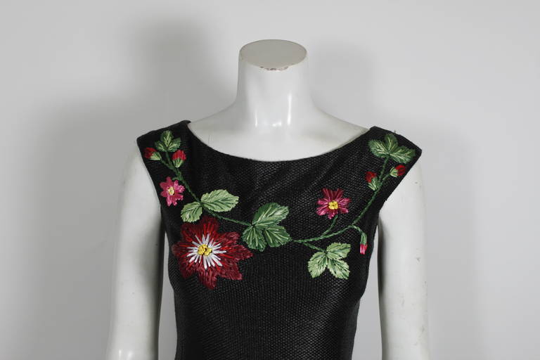 Circa 2000s raffia woven dress from Moschino. A lovely, vibrant floral pattern pops on a black background. Fully lined. Zips in back. 

