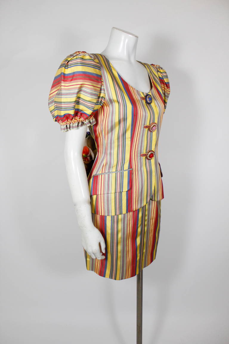 This lovely rainbow candy striped suit from Moschino Couture is not only beautifully tailored, colorful, and chic, but also features Franco Moschino’s signature whimsy with the silk floral bustle on the jacket. Jacket has three embellished buttons.