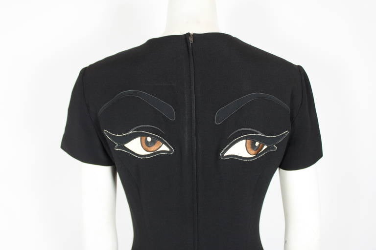 A fabulous black rayon dress from Moschino Couture done with embroidered eye embellishment. Short sleeve sheath dress. Back zipper closure. 
 